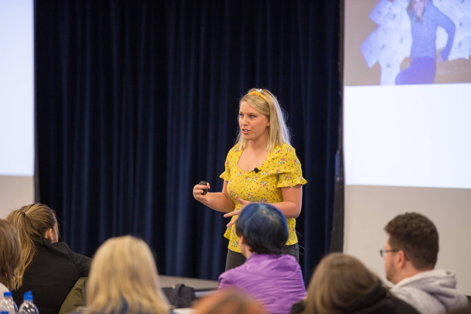 A speaker speaking to a group of students sitting at tables